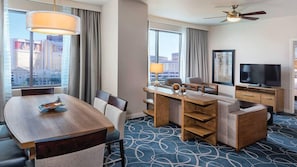 Ett hotellrum med en matplats, en soffa, en TV och utsikt över staden.