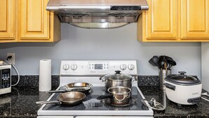 A kitchen with a stove, pots, a slow cooker, and wooden cabinets. - Family and Business Friendly Home near Great Mall & BART - 2640 (San Jose)