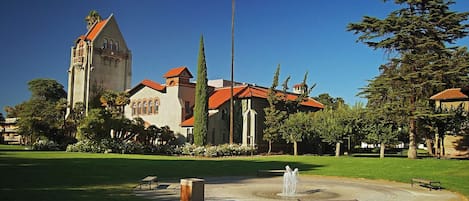 A historic building with a tower, surrounded by a well-maintained lawn and a fountain.
