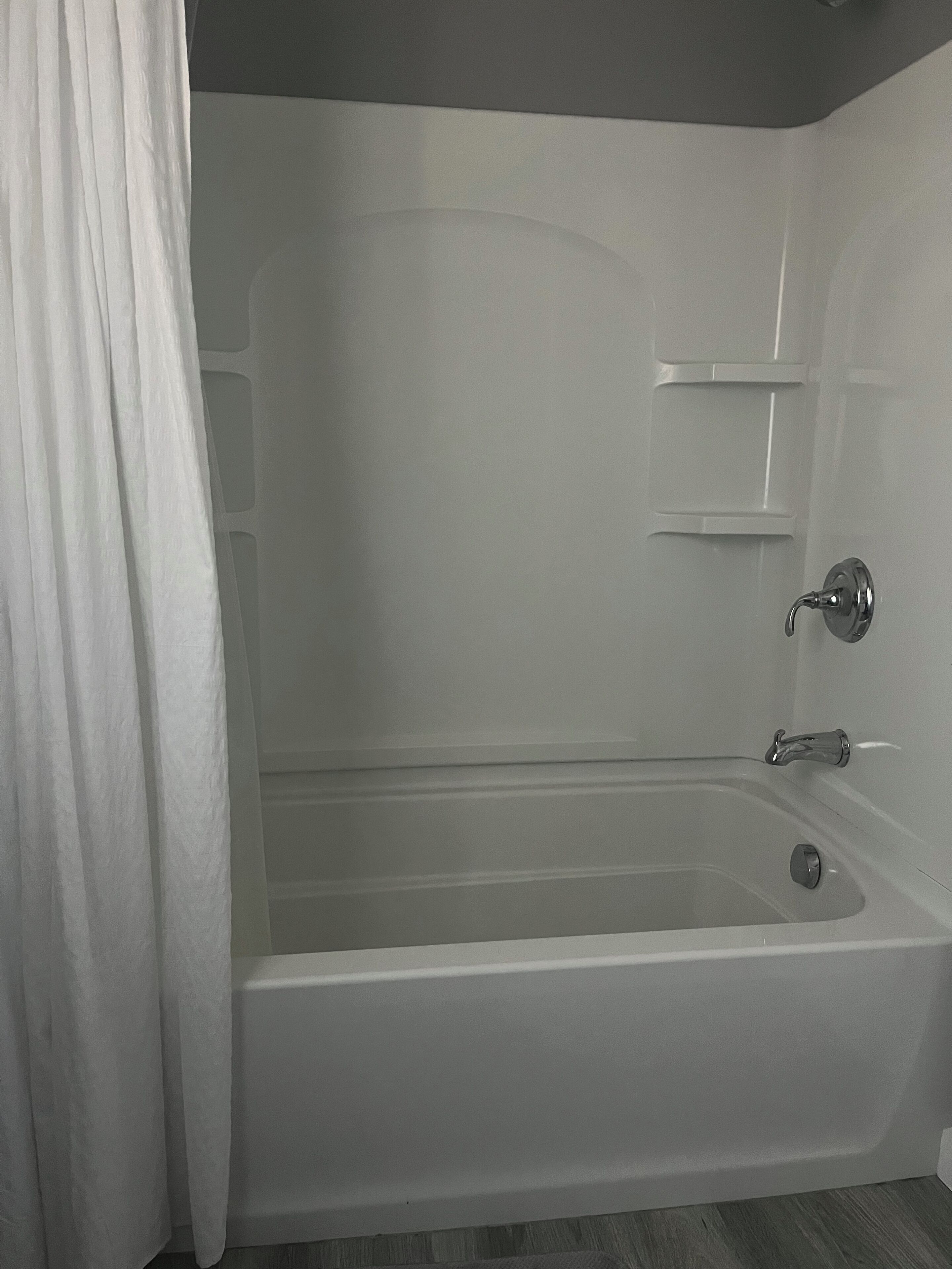 Een moderne badkamer met een bad, een douche en een toilet.
