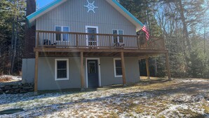 Une maison à deux étages avec un balcon, une cheminée et un drapeau américain.