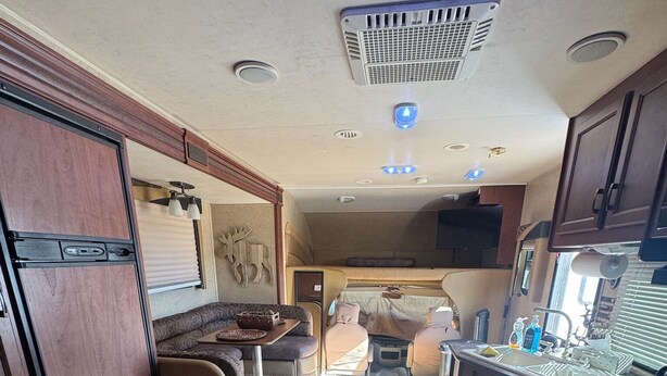 A compact RV kitchen with a stove, sink, and a small dining area. - Cozy RV stay on a South Gilbert Mini Farm (Gilbert)