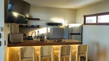 Una cocina moderna con televisión de pantalla plana, horno integrado y un comedor con cuatro sillas de madera.