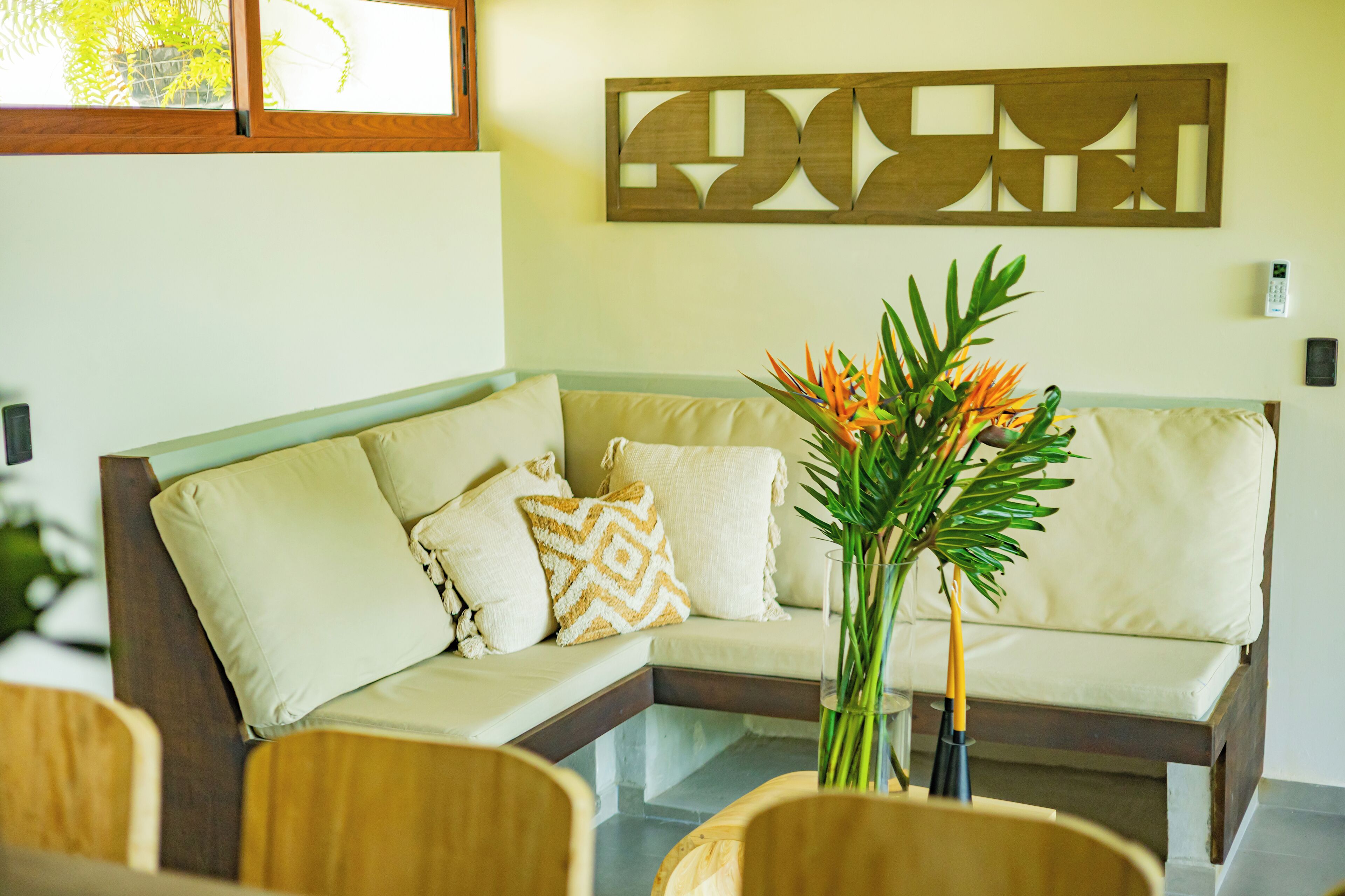A modern living room with a sectional sofa, decorative pillows, a glass coffee table, and a wall-mounted abstract art piece.