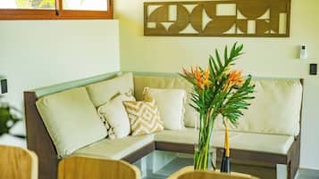 A modern living room with a sectional sofa, decorative pillows, a glass coffee table, and a wall-mounted abstract art piece.