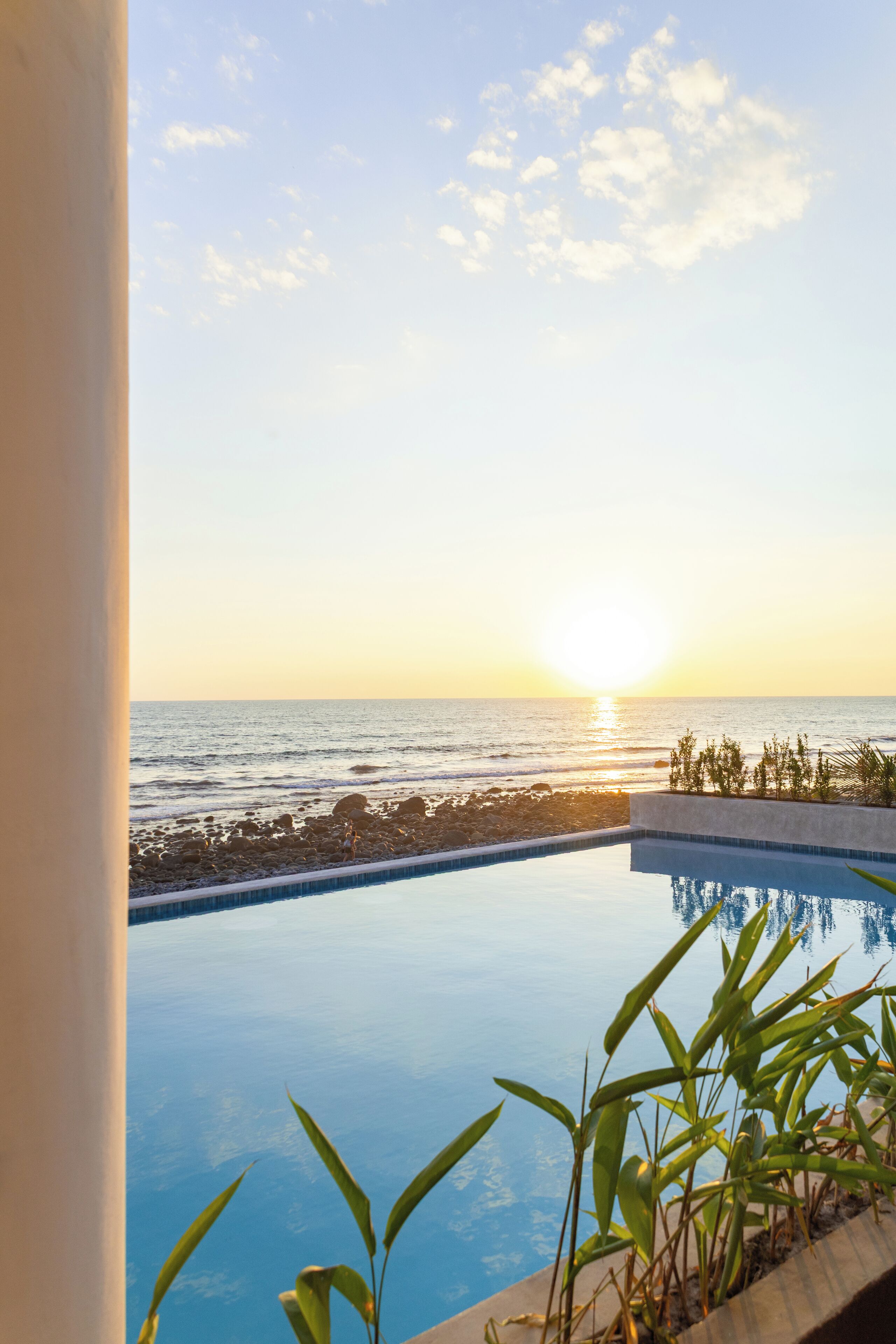 Uma piscina com vista para o oceano ao pôr do sol.