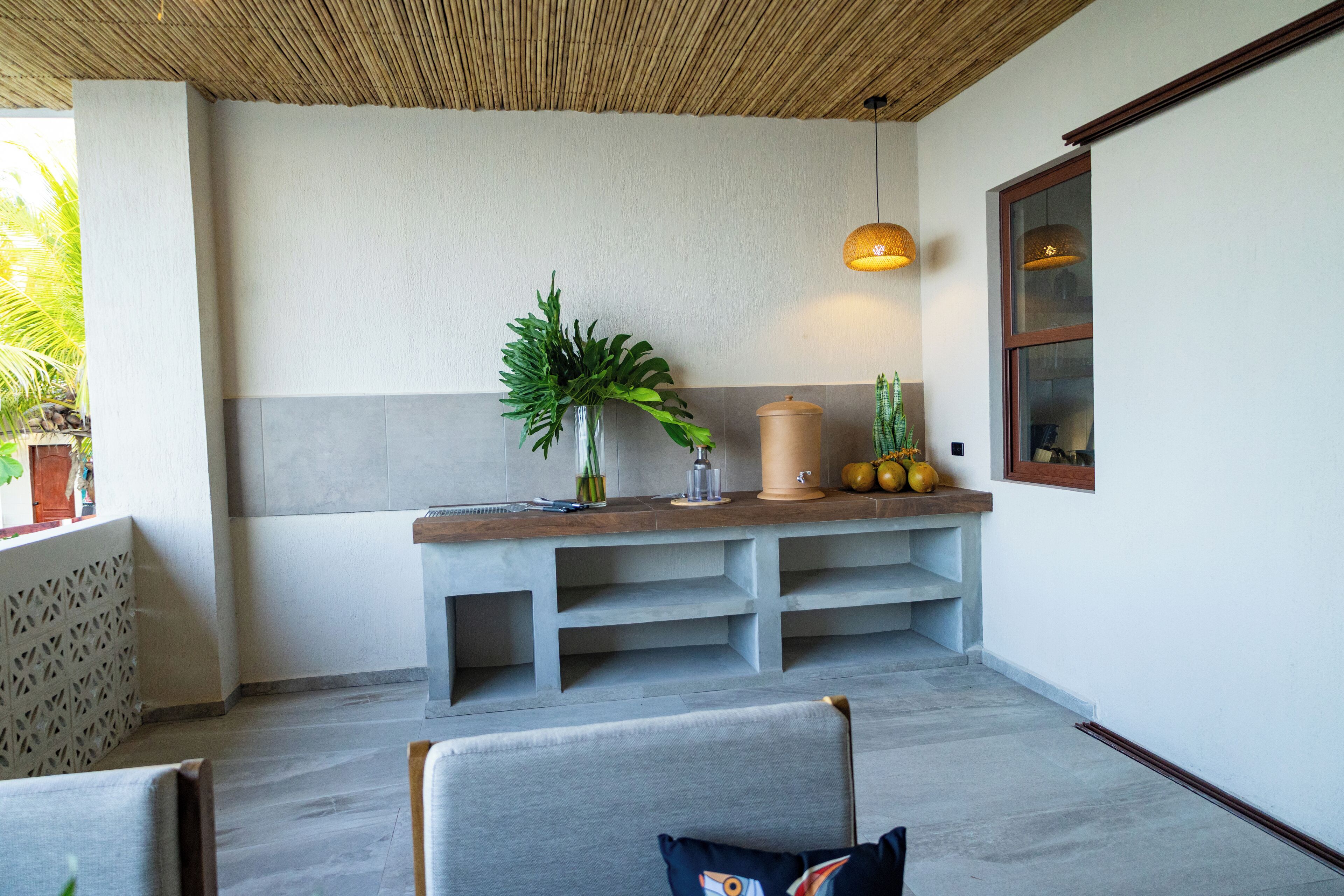 Un interior moderno con un banco de hormigón, una planta en maceta y una lámpara colgante.