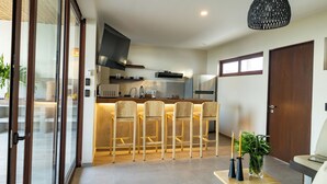 Una cocina moderna con una isla central, taburetes de bar y un comedor con sofá.