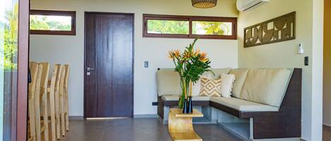 A modern living room with a sofa, a wooden coffee table, a decorative wall piece, and a ceiling light.