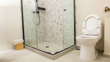 Un baño moderno con ducha de vidrio, inodoro blanco y azulejos estampados.
