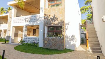 A modern building with a stone facade, a wooden balcony, and a paved courtyard.