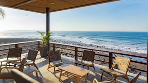 Une terrasse au bord de la plage, avec des meubles en bois et une vue sur l’océan.