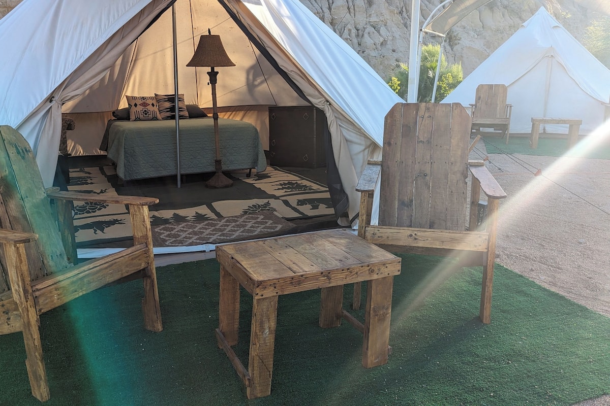 Une tente équipée d’un lit, d’une table et de deux chaises.