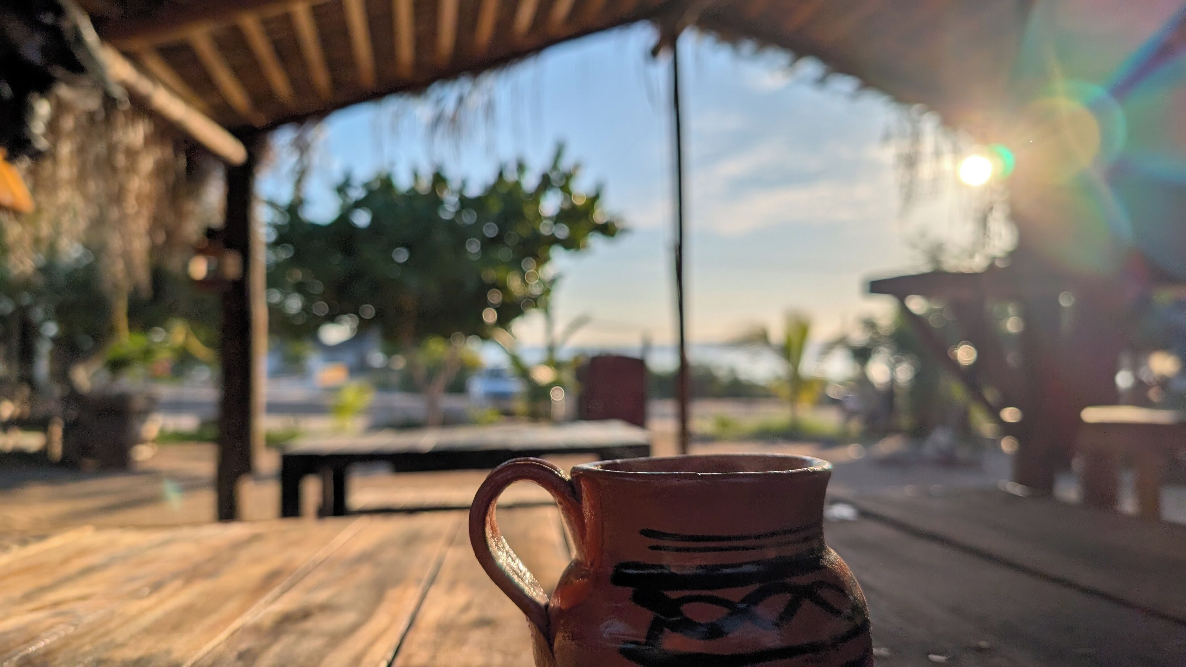 A rustic outdoor setting with a wooden table and a ceramic mug.