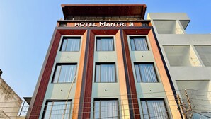 A multi-story hotel with a modern design, featuring large windows and a prominent sign reading "HOTEL MANTRI". - Hotel Mantri Ji (Ujjain)