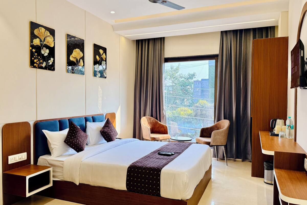 Ein Hotelzimmer mit einem großen Bett, einem Schreibtisch, zwei Stühlen, einem Fernseher und Bildern an der Wand.