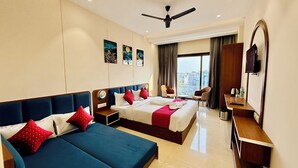 A hotel room with a bed, a sofa, a desk, and a TV. - Hotel Mantri Ji (Ujjain)