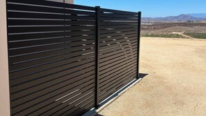A modern building with a black metal fence and a clear view of a mountainous landscape. - Relaxing Wine Country Stay - Hot Tub - Agave Farm (Temecula)