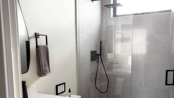 Un bagno moderno con doccia vetrata, lavandino bianco e water.
