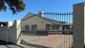 Propiedad amurallada con entrada pavimentada y un edificio con techo de tejas.