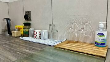 A kitchen counter with a coffee maker, a box of Freshpak, a jar of sugar, and a bottle of Renew Hygiene hand wash.