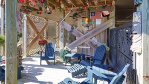 A wooden deck with Adirondack chairs, a small table, and a sign reading "Tiki Bar". - Coastal Charm Awaits in Tiki Time on Topsail! (North Topsail Beach)