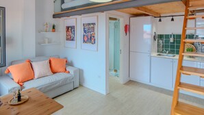 Een modern appartement met een slaapkamer op entresol, een eethoek en een keuken.