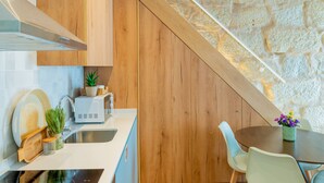 Eine moderne Küche mit Holzschränken, einer Wand aus Stein und einem Essbereich mit Tisch und Stühlen.
