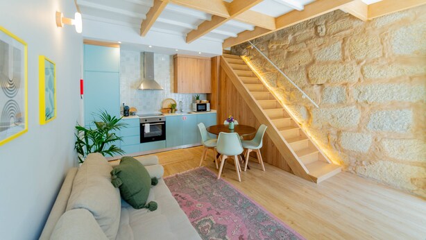 Ein modernes Interieur mit Küche, Essbereich und einer Wendeltreppe an einer Steinwand.