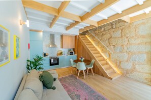 Ein modernes Interieur mit Küche, Essbereich und einer Wendeltreppe an einer Steinwand.