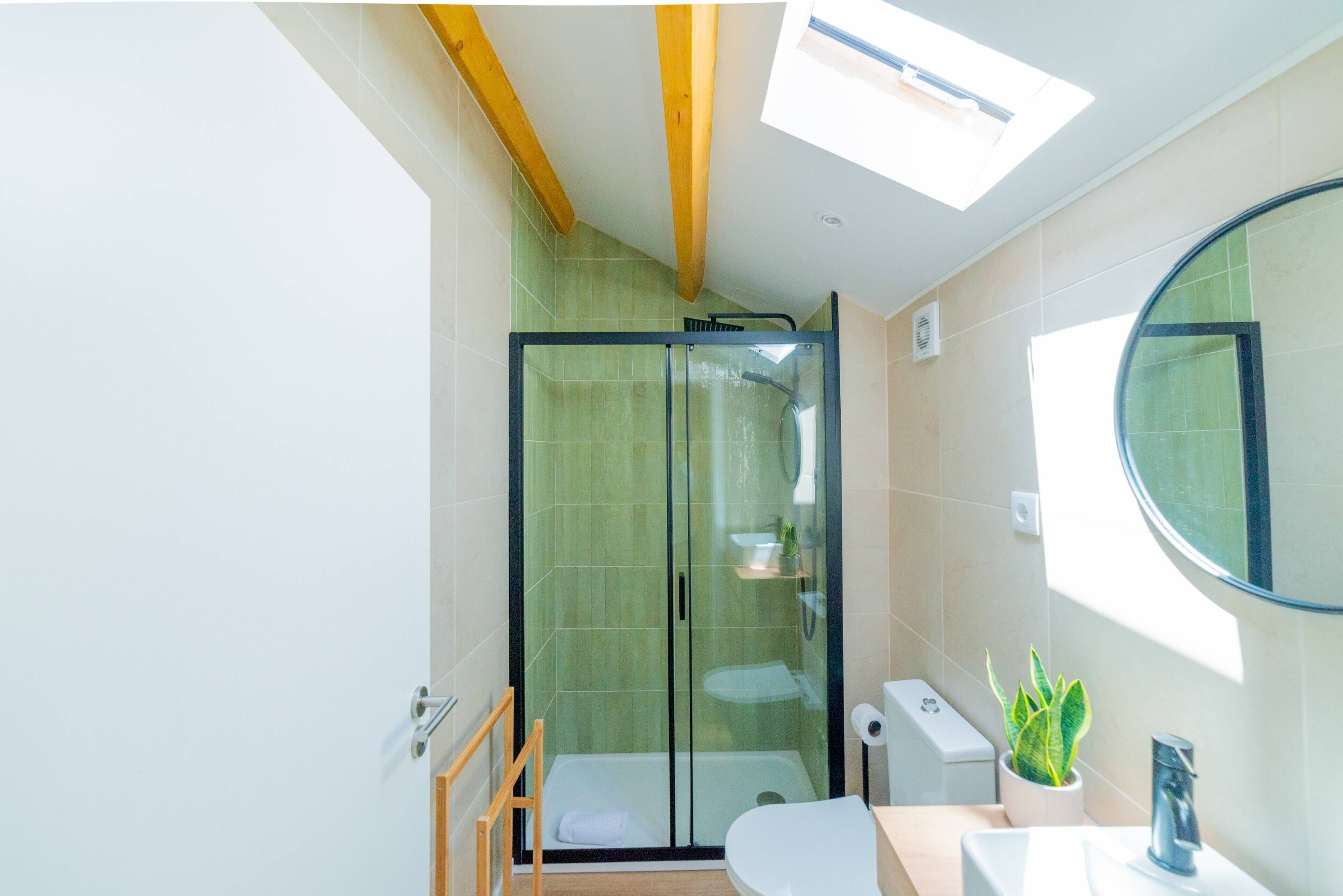 Une salle de bain moderne avec une douche à parois de verre, des toilettes, un lavabo et un miroir.