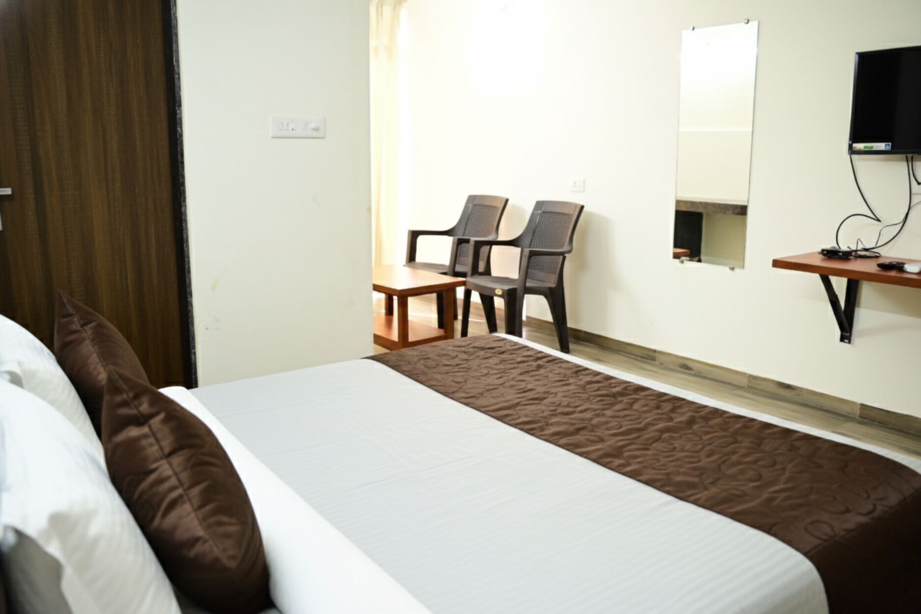 A hotel room with a bed, a desk, two chairs, a television, and a small table.