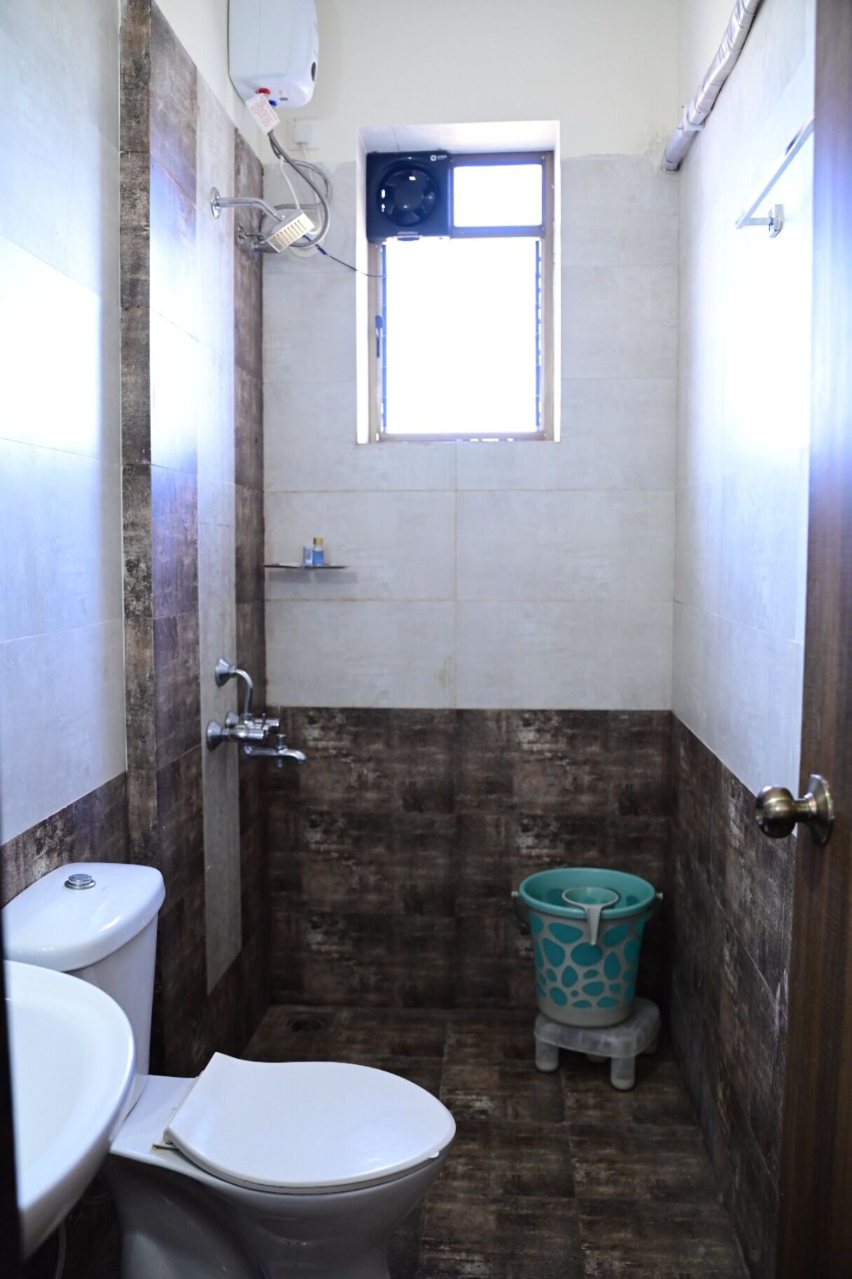 A small bathroom with a toilet, a sink, a shower, and a window.