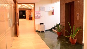 Un couloir d’hôtel avec un plancher en bois, un extincteur, un panneau indiquant qu’il est interdit de fumer et une plante en pot.