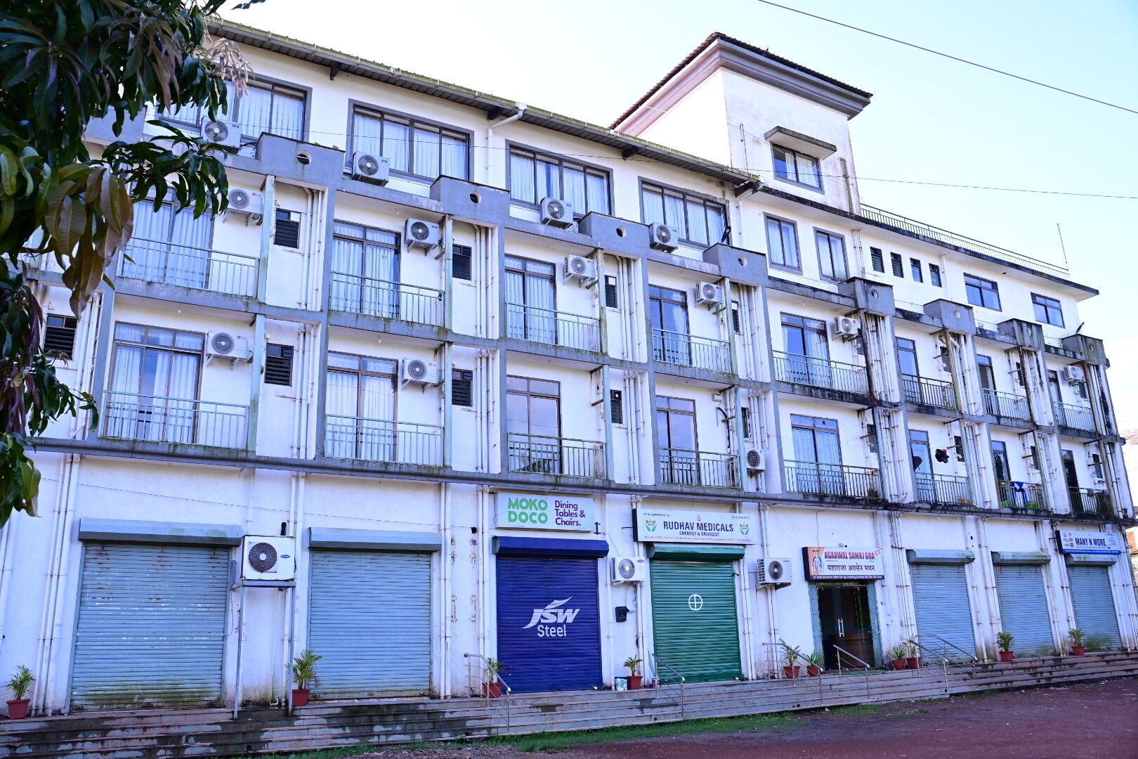 A multi-story building with several closed shop fronts, including a steel company and a medical practice.