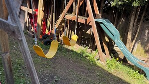 A wooden play structure with a slide and swings. - Cedar-Cottage Comfort Suite (Vancouver)