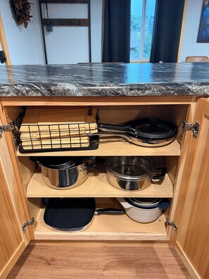 A kitchen with wooden cabinets, a granite countertop, and various cooking utensils.