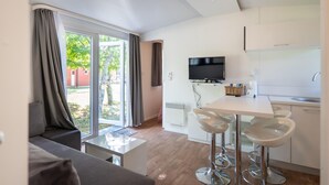 Eine moderne Küche mit Flachbildfernseher, weißen Schränken und einer Essecke mit Barhocker.
