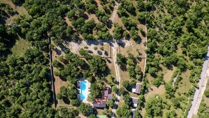Vista aérea de um bairro residencial com piscina, várias casas e vegetação ao redor.