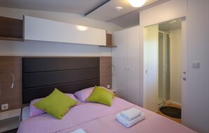 A modern bedroom with a large bed, a headboard, a small bedside table, and a built-in shelf above the bed.