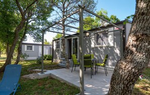 A patio area with a pergola, outdoor seating, and a small building with a window.