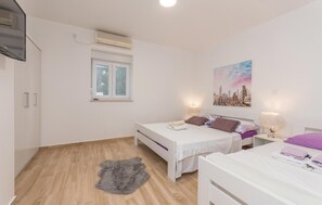 A bedroom with two beds, a window, an air conditioning unit, and a cityscape painting. - Beautiful apartment in Turanj with WiFi (Turanj)