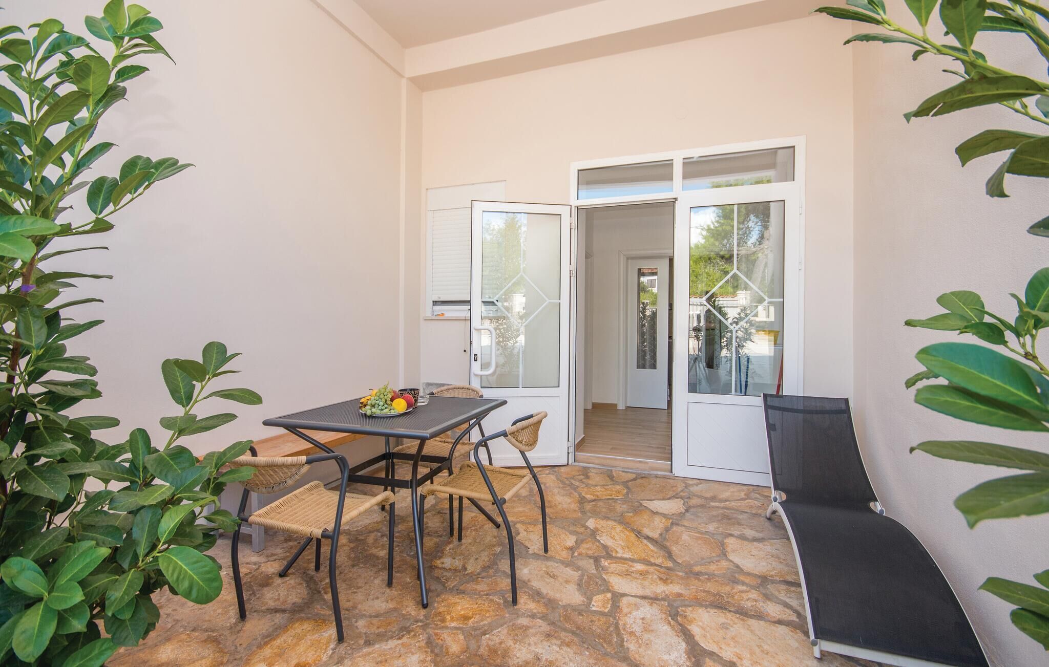 A patio area with a table and chairs, a bench, and a door leading to an outdoor space.