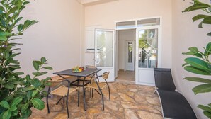 Un patio con mesa y sillas, un banco y una puerta que da a un espacio exterior.