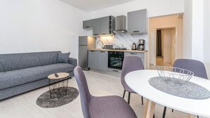 Una sala de estar moderna con un sofá gris, una mesita redonda y dos sillones.