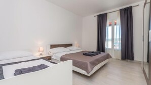 Habitación de hotel con dos camas, un ventanal grande con cortinas y un armario.