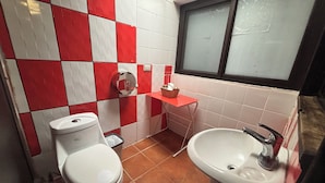 Une salle de bain avec des toilettes, un lavabo et des murs recouverts de carreaux rouges et blancs.