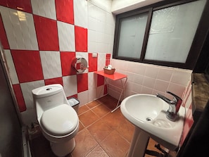 Un bagno con il water, un lavandino e pareti piastrellate bianche e rosse.