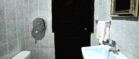Un baño pequeño con inodoro, lavamanos y un espejo en la pared.