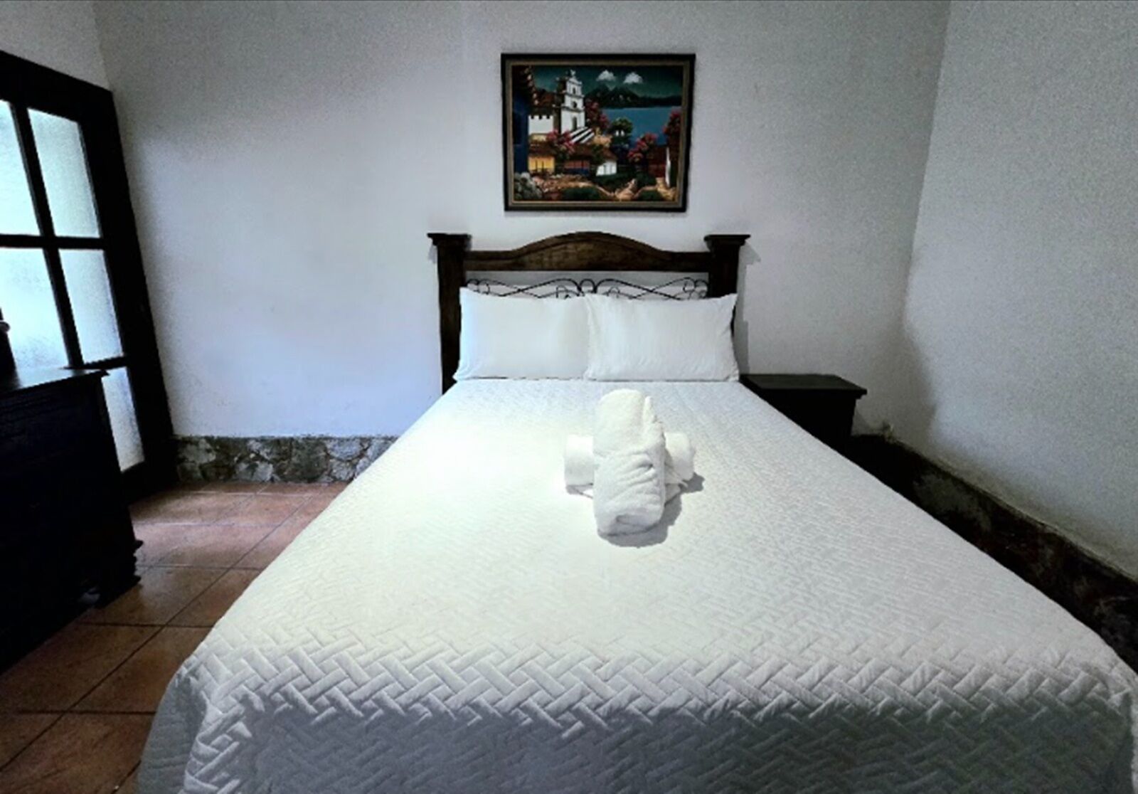 A neatly made bed with a white bedspread and a decorative pillow.
